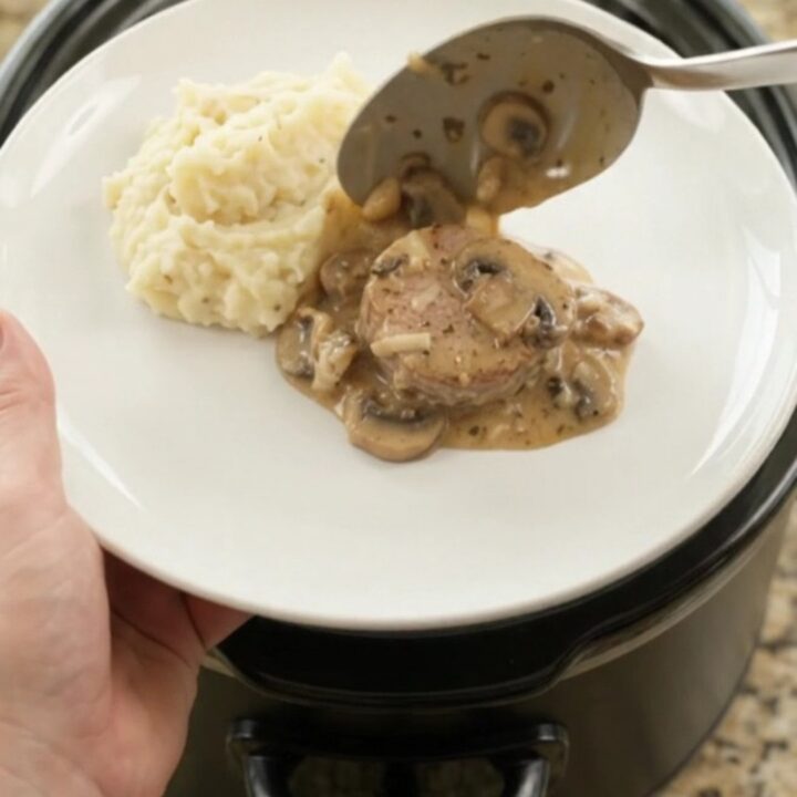 Crockpot filled with creamy Gruyère ranch pork medallions, bubbling and steaming