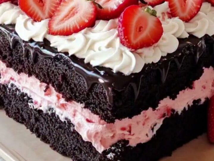A decadent square chocolate cake topped with whipped cream rosettes and fresh strawberries.
