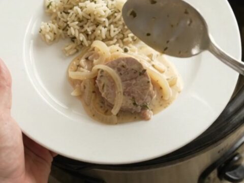 Slow cooker full of pork medallions in creamy Parmesan sauce with onions and thyme