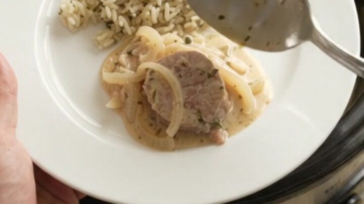 Slow cooker full of pork medallions in creamy Parmesan sauce with onions and thyme