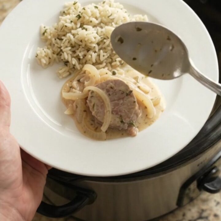 Slow cooker full of pork medallions in creamy Parmesan sauce with onions and thyme