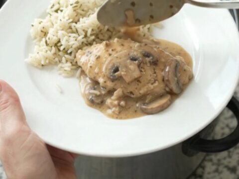 Creamy Parmesan ranch mushroom turkey cutlets in a slow cooker, garnished with fresh herbs, with steam rising.