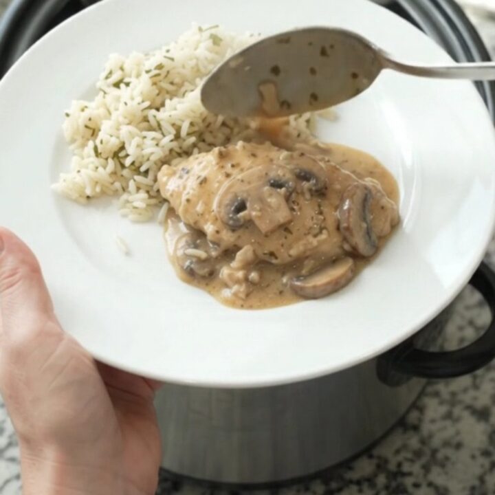 Creamy Parmesan ranch mushroom turkey cutlets in a slow cooker, garnished with fresh herbs, with steam rising.