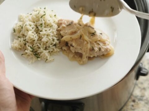 Slow cooker filled with creamy Parmesan French onion turkey cutlets, garnished with thyme