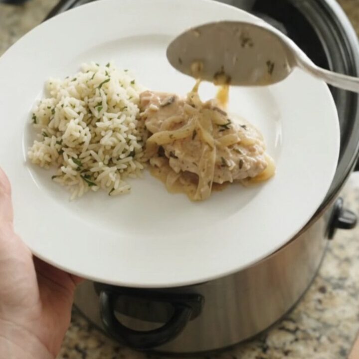 Slow cooker filled with creamy Parmesan French onion turkey cutlets, garnished with thyme