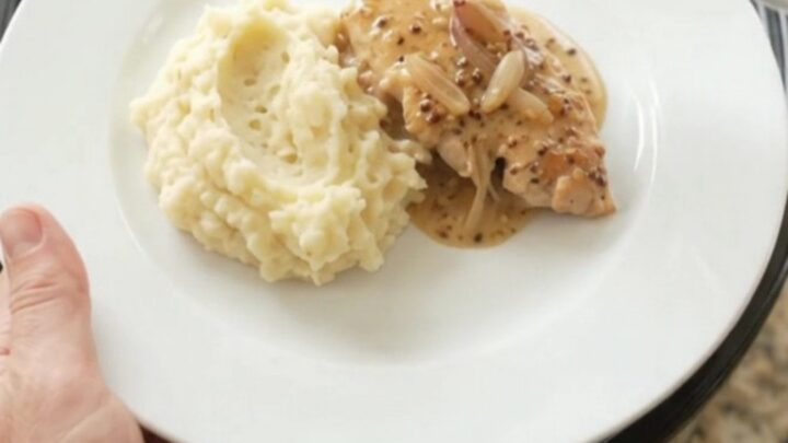 Slow cooker turkey cutlets in a creamy Gruyère sauce with honey-Dijon glaze, served on a white plate.