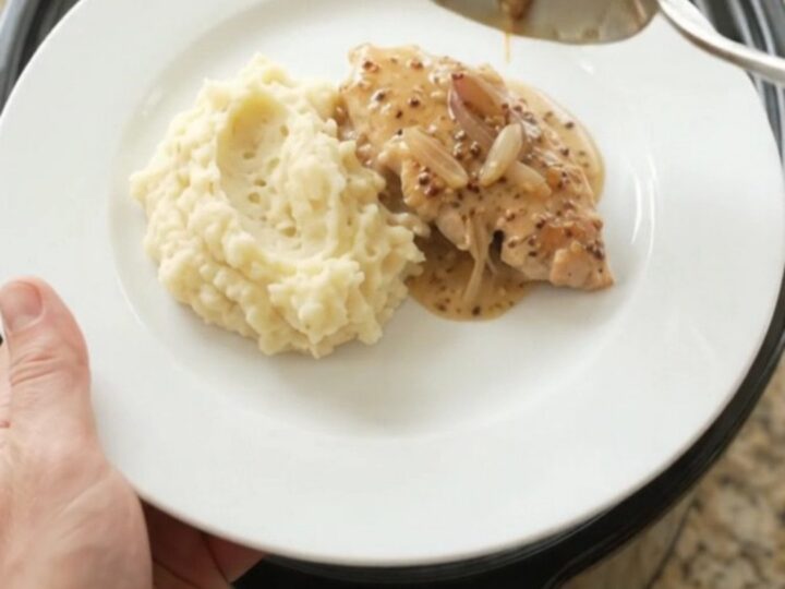 Slow cooker turkey cutlets in a creamy Gruyère sauce with honey-Dijon glaze, served on a white plate.