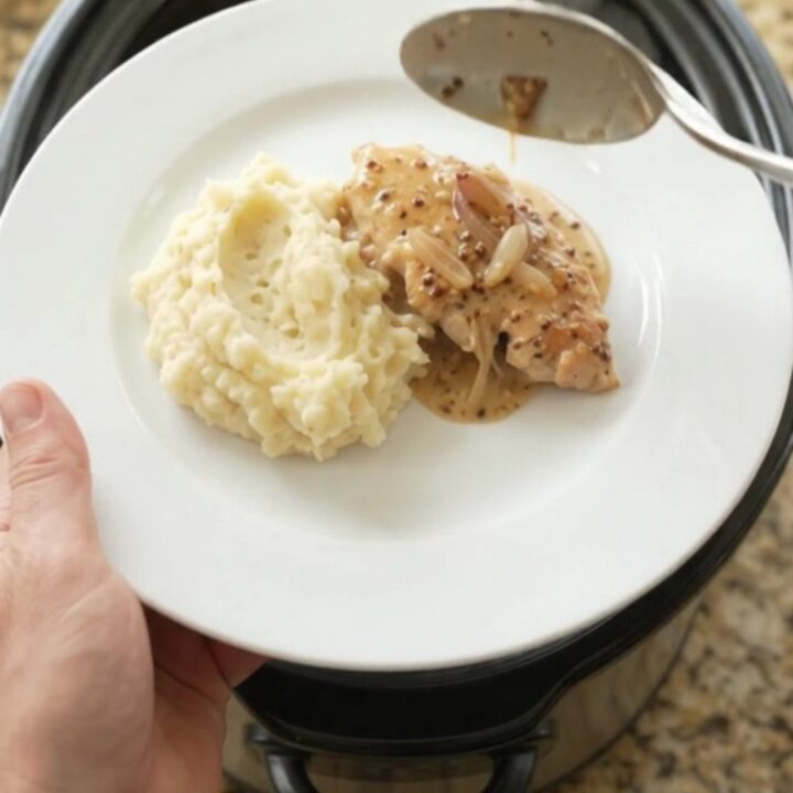 Slow cooker turkey cutlets in a creamy Gruyère sauce with honey-Dijon glaze, served on a white plate.