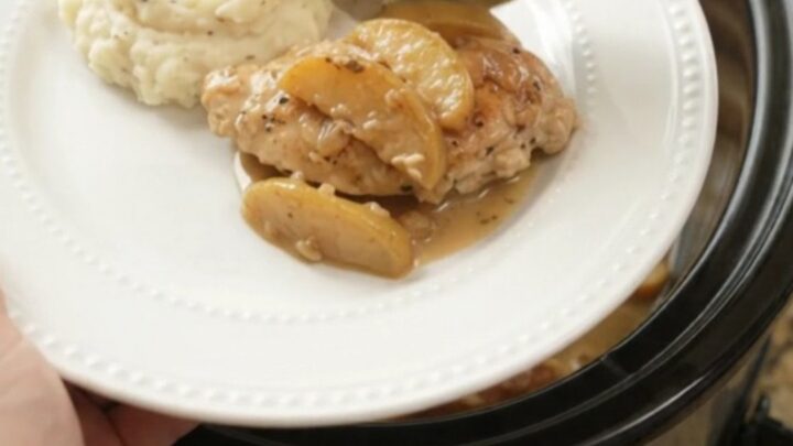 Slow cooker chicken cutlets with apples and cream sauce in a black ceramic crockpot