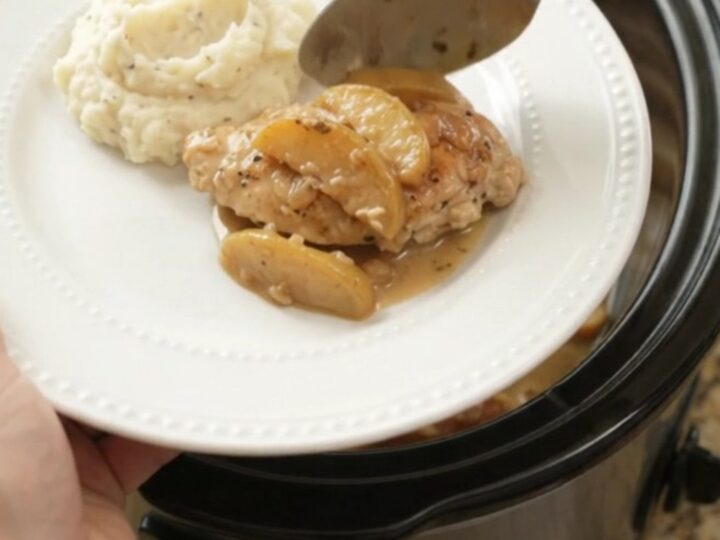 Slow cooker chicken cutlets with apples and cream sauce in a black ceramic crockpot