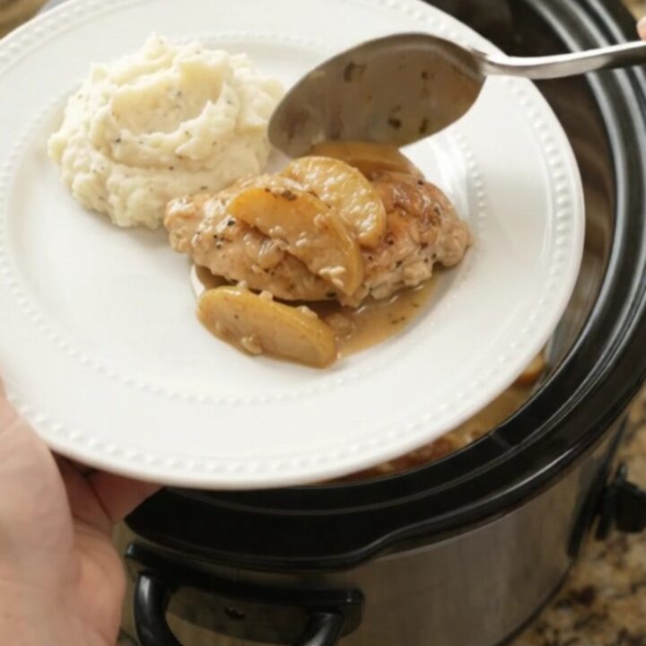 Slow cooker chicken cutlets with apples and cream sauce in a black ceramic crockpot