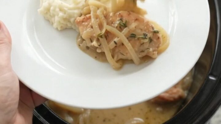 Butter cream French onion chicken cutlets in a slow cooker, topped with melted onions and thyme.