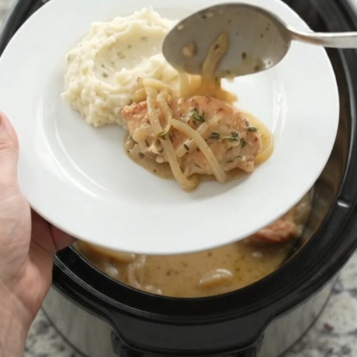 Butter cream French onion chicken cutlets in a slow cooker, topped with melted onions and thyme.