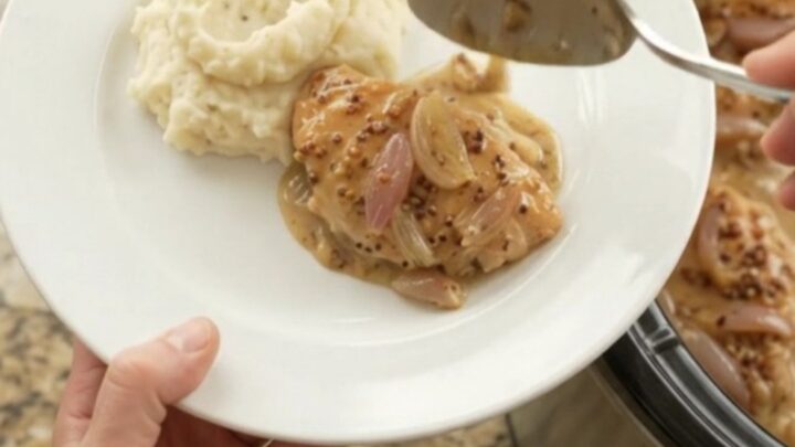 Slow-cooker honey Dijon chicken cutlets in a creamy sauce with shallots, in a black crock