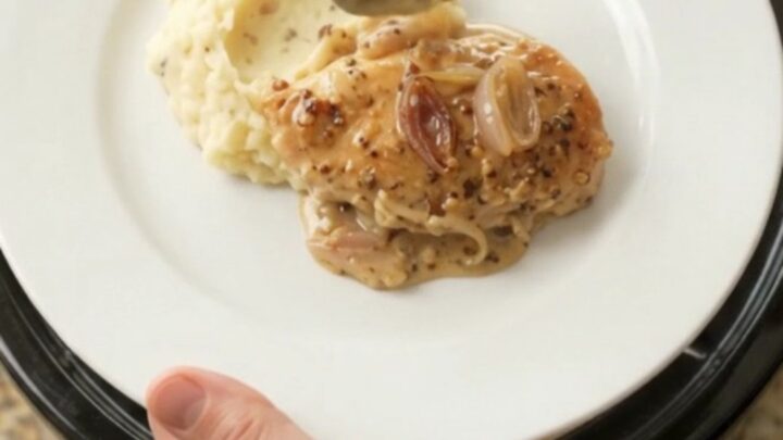 Crockpot chicken cutlets in creamy honey-Dijon Gruyère sauce, bubbling in the slow cooker.