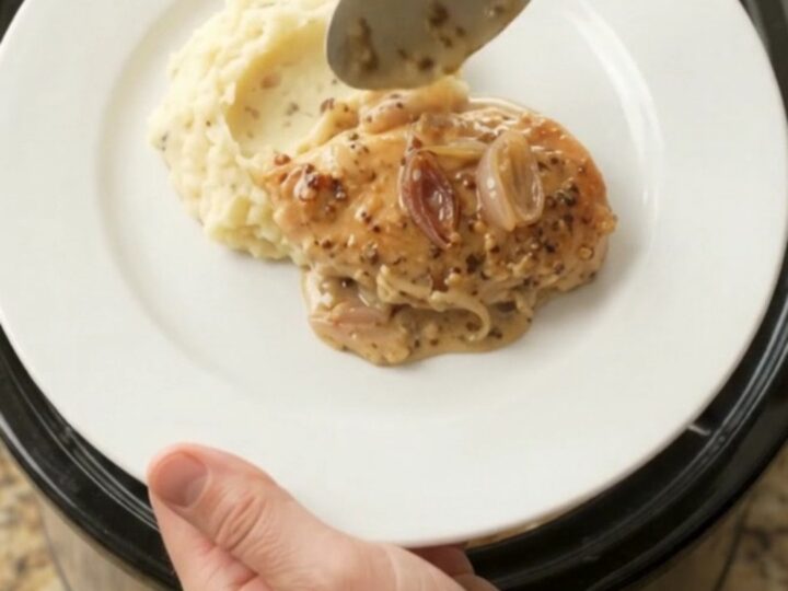 Crockpot chicken cutlets in creamy honey-Dijon Gruyère sauce, bubbling in the slow cooker.