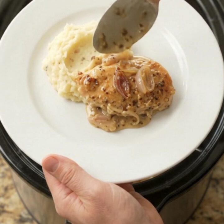 Crockpot chicken cutlets in creamy honey-Dijon Gruyère sauce, bubbling in the slow cooker.