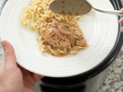 Crockpot sour cream honey Dijon chicken cutlets in a black slow cooker, creamy sauce with shallots