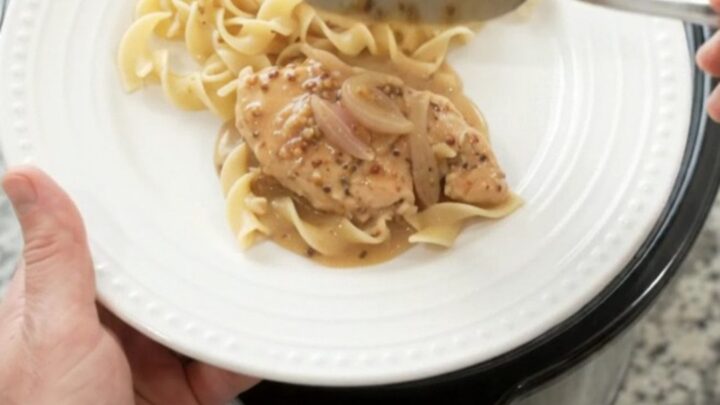 Crockpot sour cream honey Dijon chicken cutlets in a black slow cooker, creamy sauce with shallots