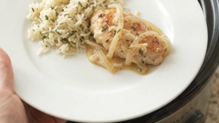 Slow cooker chicken cutlets in a creamy Parmesan onion sauce, with melted onions and thyme in a black Crockpot