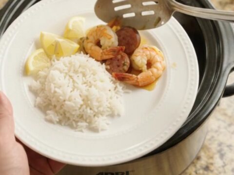 Slow cooker filled with shrimp, sausage, and potatoes in a golden butter sauce