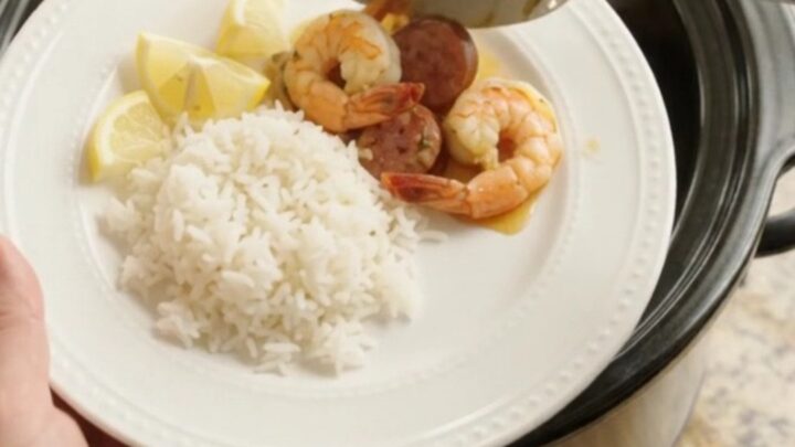 Slow cooker filled with shrimp, sausage, and potatoes in a golden butter sauce