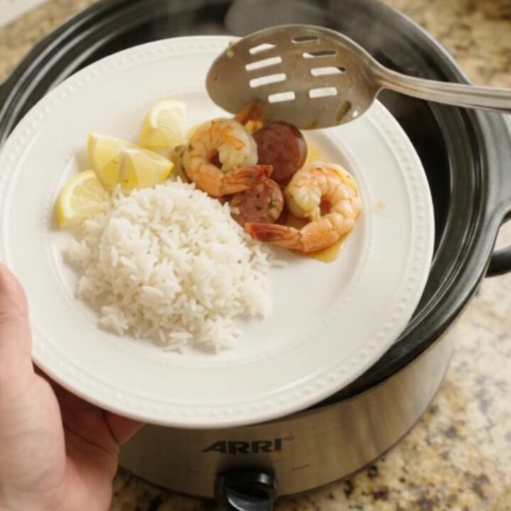 Slow cooker filled with shrimp, sausage, and potatoes in a golden butter sauce