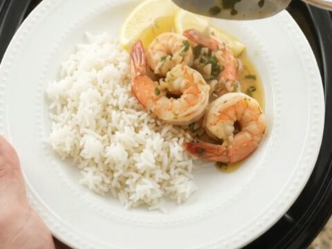 Slow cooker filled with shrimp, corn, and potatoes in herb butter sauce