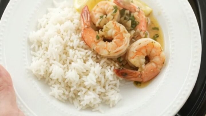 Slow cooker filled with shrimp, corn, and potatoes in herb butter sauce