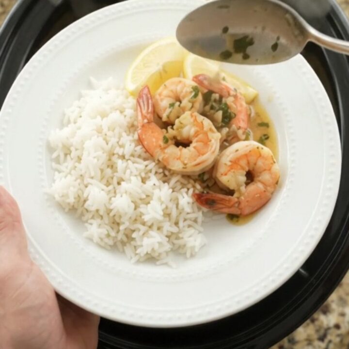 Slow cooker filled with shrimp, corn, and potatoes in herb butter sauce
