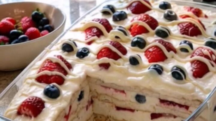 A 9x13 glass dish filled with layers of cream, pudding, graham crackers, and fresh berries.