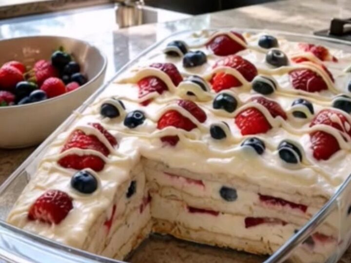 A 9x13 glass dish filled with layers of cream, pudding, graham crackers, and fresh berries.