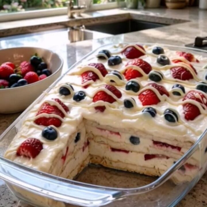 A 9x13 glass dish filled with layers of cream, pudding, graham crackers, and fresh berries.