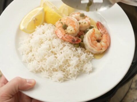 Slow cooker shrimp with lemon, capers, and herb butter in a black crock