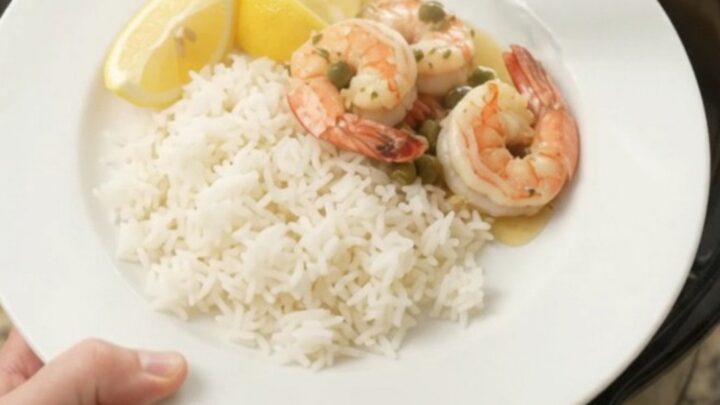 Slow cooker shrimp with lemon, capers, and herb butter in a black crock
