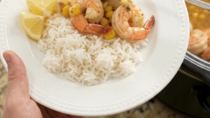 Slow cooker filled with shrimp, corn, and garlic in a golden butter sauce