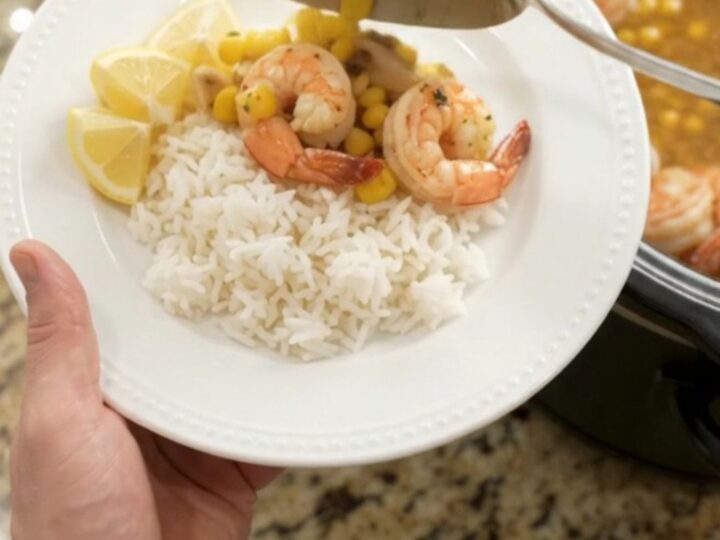 Slow cooker filled with shrimp, corn, and garlic in a golden butter sauce