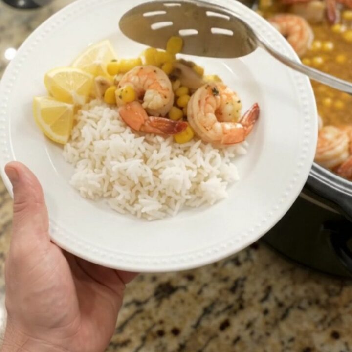 Slow cooker filled with shrimp, corn, and garlic in a golden butter sauce