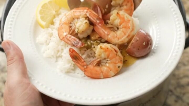 Slow cooker full of snow crab, shrimp, corn, and potatoes in golden butter sauce.