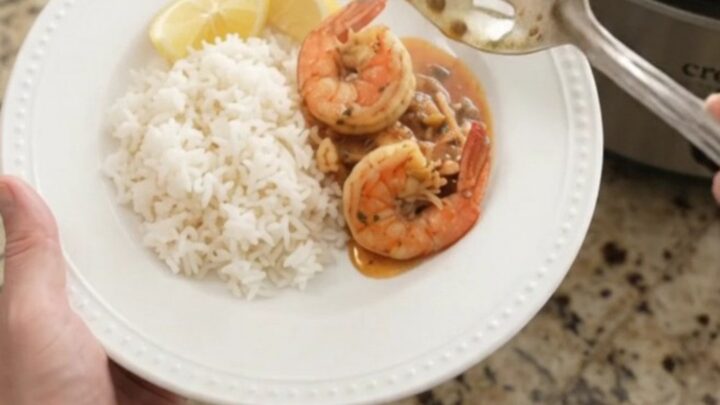 Slow cooker filled with snow crab, shrimp, corn, and potatoes in a red butter sauce