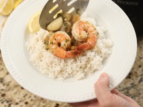 Slow cooker filled with snow crab, shrimp, corn, and garlic in a golden butter sauce