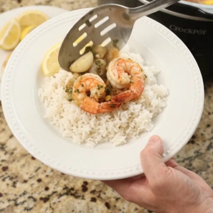 Slow cooker filled with snow crab, shrimp, corn, and garlic in a golden butter sauce