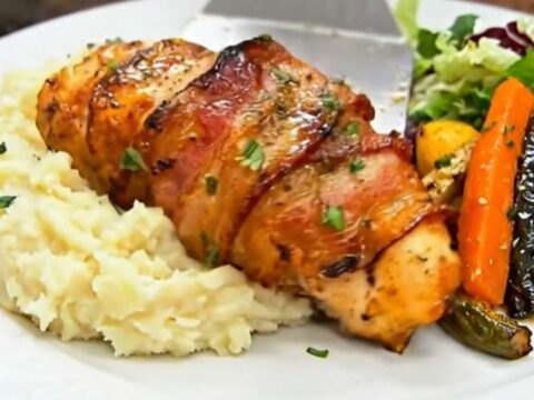 A golden honey-glazed bacon-wrapped chicken breast served over creamy mashed potatoes.