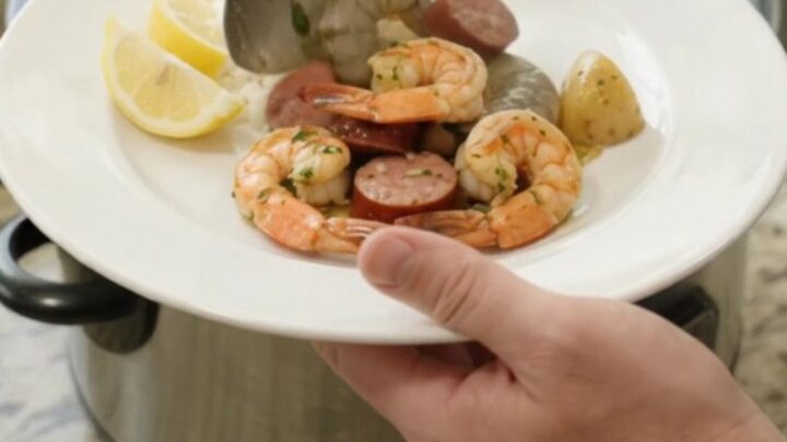 Slow cooker filled with snow crab, shrimp, and sausage in a buttery sauce