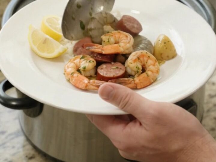 Slow cooker filled with snow crab, shrimp, and sausage in a buttery sauce