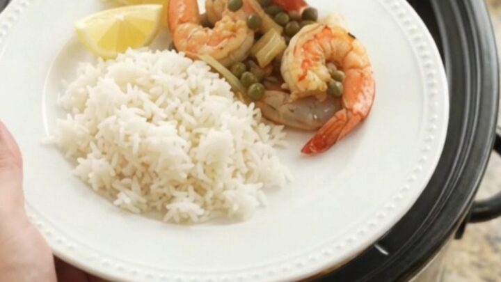 Slow cooker filled with snow crab and shrimp in a red Cajun butter sauce with lemon slices