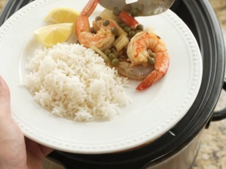 Slow cooker filled with snow crab and shrimp in a red Cajun butter sauce with lemon slices