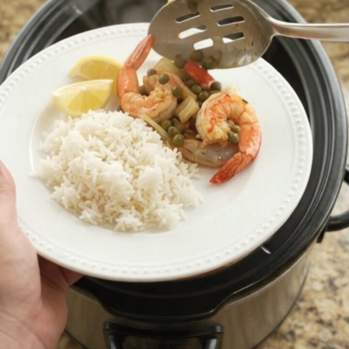 Slow cooker filled with snow crab and shrimp in a red Cajun butter sauce with lemon slices