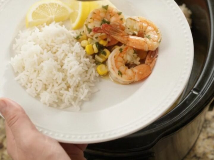 Slow cooker filled with snow crab legs, shrimp, corn, and garlic in a golden butter sauce