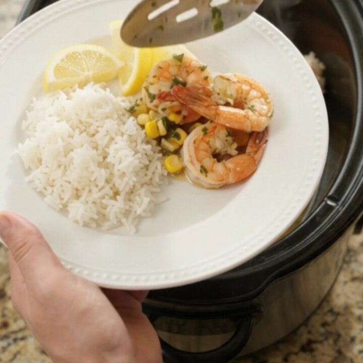 Slow cooker filled with snow crab legs, shrimp, corn, and garlic in a golden butter sauce